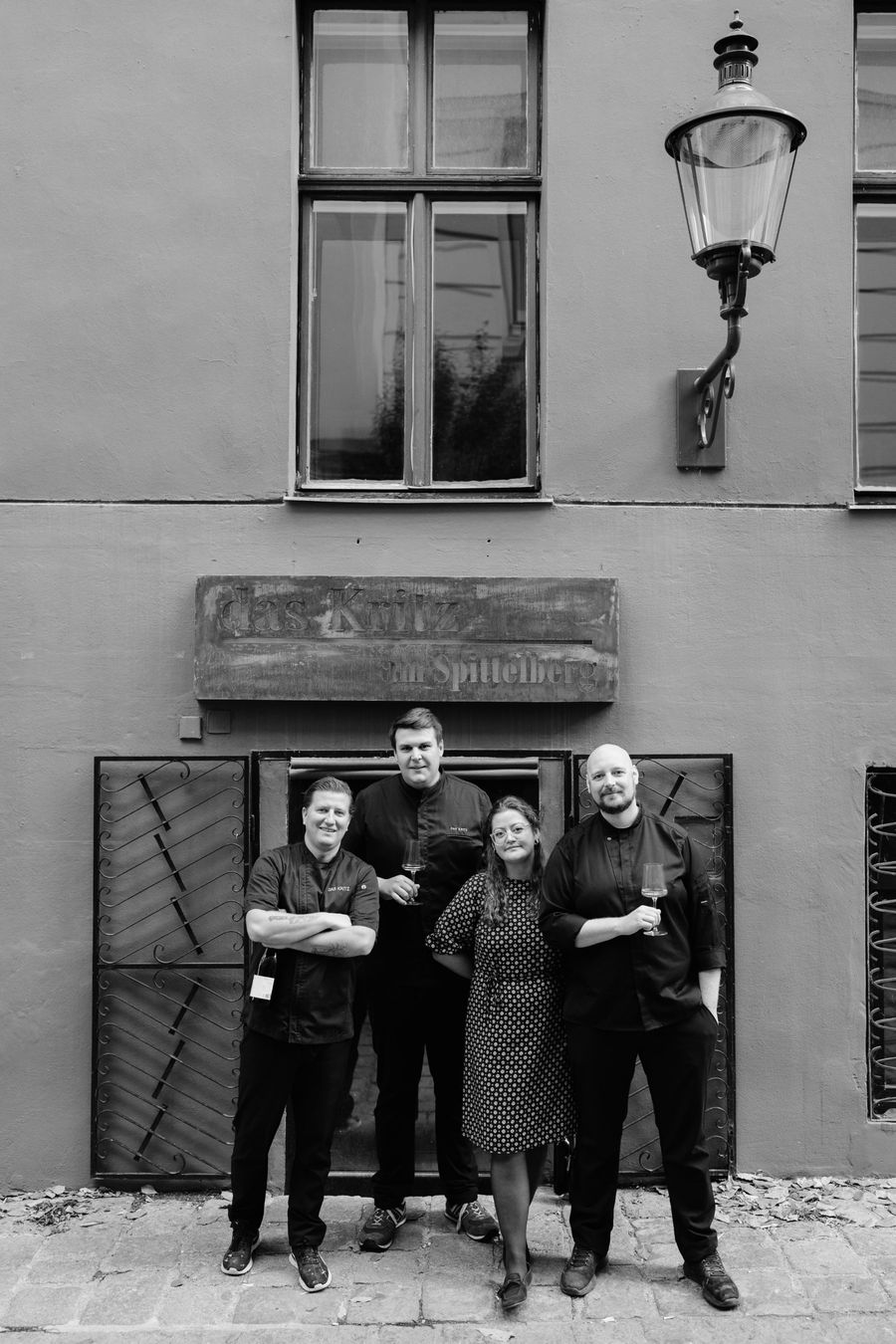 The façade at Spittelberg with a street lamp and the sign “das Kritz am Spittelberg”, with the das Kritz team in front